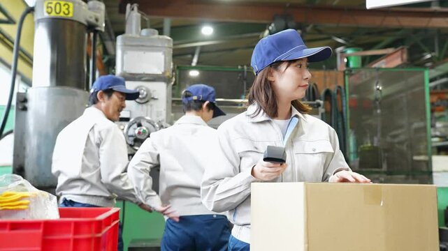 工場でハンディターミナルを使って製品を検査する女性作業員