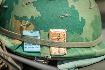 Camouflage military helmet with a fabric cover in green and brown patches. 