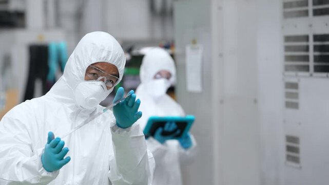 半導体工場でシリコンウエハーを検査する防護服を着た男性作業員