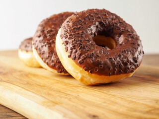 Sweet tasty chocolate donuts on wooden board. Popular desert and snack. Fine bakery product.