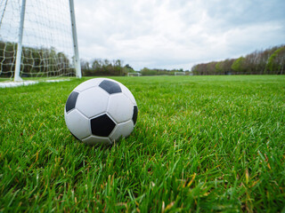 Classic style soccer or football on neatly cut green grass with small training goal posts in the background. Play area in a park. Sport and entertainment concept.