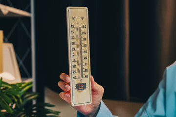 Thermometer concept. Hand Holding Vintage Thermometer Displaying Temperature in Celsius and...