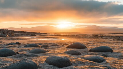 Obraz premium Sunset Beach Stones: Golden sunset over tranquil beach, smooth stones scattered on the sand, serene coastal landscape. 