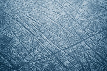 Gritty textured ice rink surface background showing a network of sharp skate marks deep cuts and scuffs from intense ice hockey play and figure skating practice under cool blue arena lighting