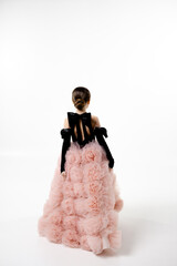 A child girl in an elegant, voluminous gown with a textured skirt and a sleek, tied back hairstyle,...
