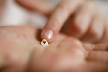 the child's fingers touch the milk tooth in the palm of the hand