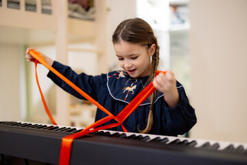 A young girl excitedly opens a gift-wrapped electronic keyboard with a red ribbon.