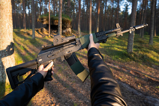 The Baltics - June 1, 2025: AK-12 assault rifle with an EOTech sight in hands in a pine forest, first-person view.