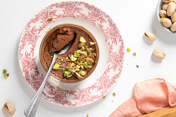 An overhead shot captures a decadent chocolate mousse adorned with pistachios