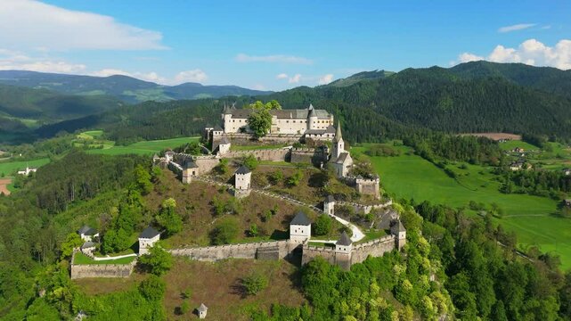Medival castle with large wall and church on top of a large protected hill in Austria, Burg Hochosterwitz, aerial video, drone footage