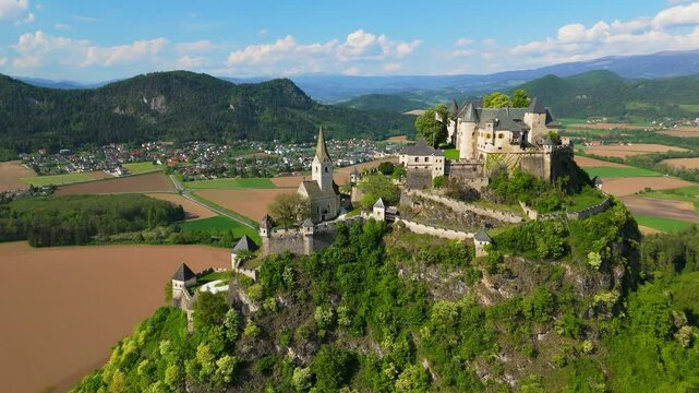 Medival castle with large wall and church on top of a large protected hill in Austria, Burg Hochosterwitz, aerial video, drone footage