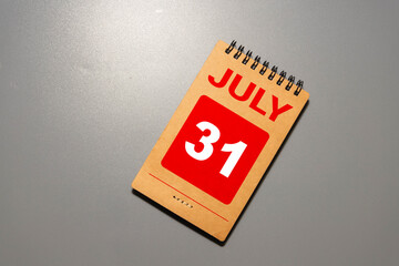July 31.Wooden calendar with date and table clock with bells.