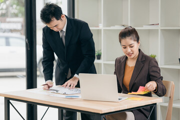 Business men and women discussing charts and graphs showing results of successful teamwork using laptops. Business strategy planning and brainstorming.