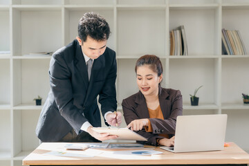 Business men and women discussing charts and graphs showing results of successful teamwork using laptops. Business strategy planning and brainstorming.
