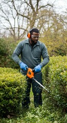 Man Trimming Hedge in Garden Outdoor with Protective Gear