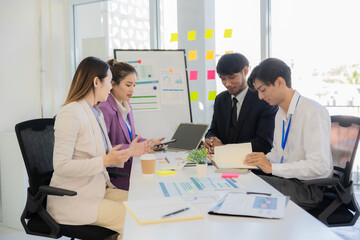 A team of professionals are reviewing financial charts, working together to analyze data for strategic planning and decision-making processes during a meeting in an office conference room.