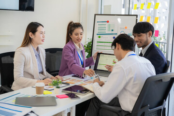 A team of professionals are reviewing financial charts, working together to analyze data for strategic planning and decision-making processes during a meeting in an office conference room.