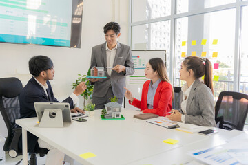 Real estate team meeting in Asia about selling a house with real estate agents at their desks in the office