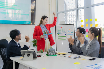 Real estate team meeting in Asia about selling a house with real estate agents at their desks in the office