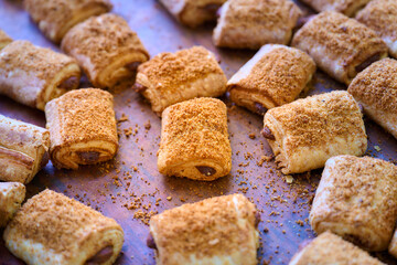 Freshly baked filled rolls on wooden surface showcasing golden pastry and crumb toppings