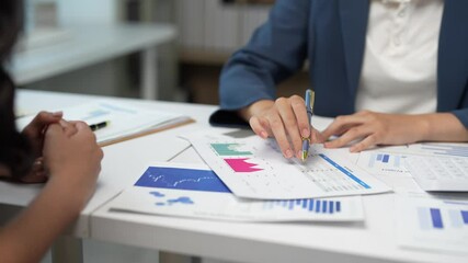 Successful businesswomen analyzing marketing data, reviewing financial documents, discussing company performance, and finalizing collaborative business agreement with confident handshake - Powered by Adobe