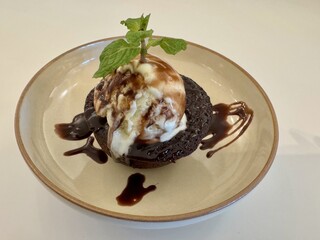 A chocolate lava molten cake served with a scoop of vanilla ice cream and melting sauce
