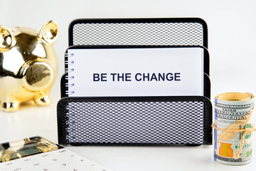 Words BE THE CHANGE on a blank sheet of notepad, a close-up view from the front