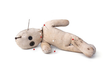 Creepy voodoo doll made from old cloth vintage style with pins from punishment stuck in body and a rusty nail stuck on head isolated on white background.
