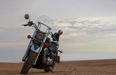 A motorcycle stands still beneath a vibrant sunset, symbolizing freedom, adventure, and the thrill...