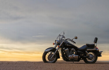 A motorcycle stands still beneath a vibrant sunset, symbolizing freedom, adventure, and the thrill of exploring new roads ahead.