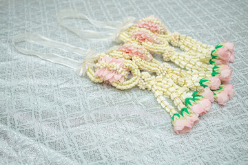 Beautiful Thai-style jasmine garland on a silver cloth background with an ancient Thai pattern.