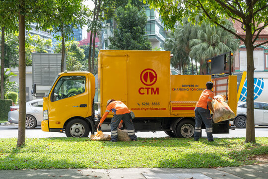 Singapore, Singapore - May 01, 2025: Yellow CTM truck with workers collecting trash on Orchard Road