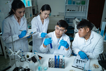 In the laboratory, a group of professional researchers gather around a chemical tube, checking...