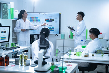 In the laboratory, a group of researchers meets to report their findings, discussing their work and preparing for future experiments, all focused on advancing science and health care.