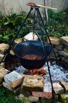 Traditional hungarian goulash in a pot hanging over a fire in a garden