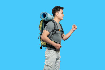 Solo Hiker: Man with backpack and sleeping pad walks against bright blue background active lifestyle
