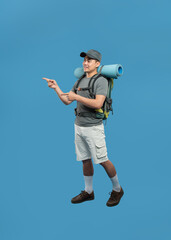 Enthusiastic hiker points towards a distant trail ready for adventure with his backpack