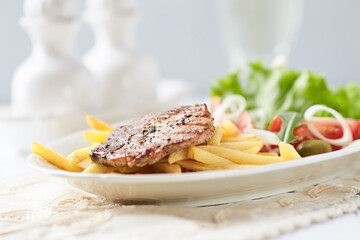Grilled Steak with french fries and fresh salad. White wooden background.	