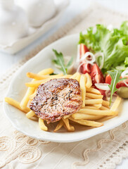 Grilled Steak with french fries and fresh salad. White wooden background.	