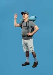 Man with a backpack waves hello ready for an adventure in the great outdoors on a blue background © Q88
