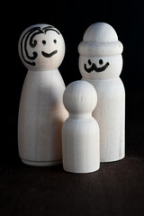 wooden peg dolls representing a family isolated on black background