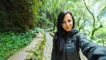Young Spanish woman taking selfie while hiking in tropical forest