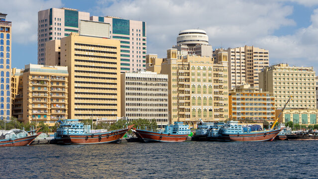 Multi-storey buildings and cargo ships on promenade along bank of Dubai Creek in Al Fahidi neighborhood of Dubai, United Arab Emirates