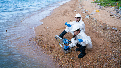 Scientists biologists and researchers in protective suits taking water samples from waste water...
