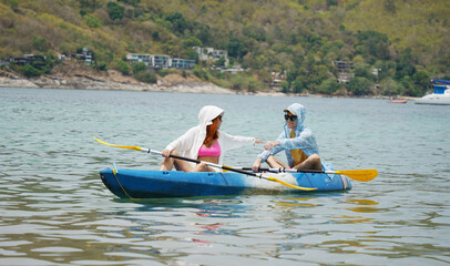 Naklejka premium The young couple are happily navigating together in a light blue kayak with yellow paddles