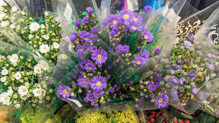 Bouquets of fresh flowers wrapped in transparent plastic with purple and white asters, ideal for florists, weddings, and romantic gifts.
