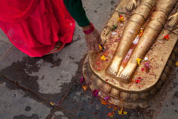 Devotee Offering Prayers at Sacred Feet of Deity