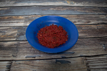 Fresh red chili sauce with herbs and spices on a bright blue plate.