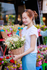 beautiful asian woman smiles while selecting a flower basket with incense and candles to worship at Wat Chedi Luang during the traditional khan dok festival, Chiang mai