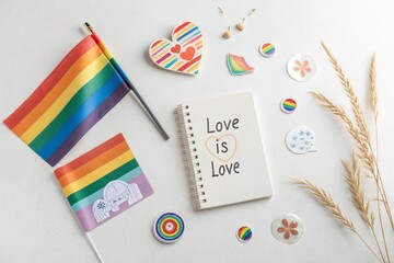 Rainbow flags, pins, inclusive stickers, and a journal with the words “Love is Love.” Soft tones, natural light.